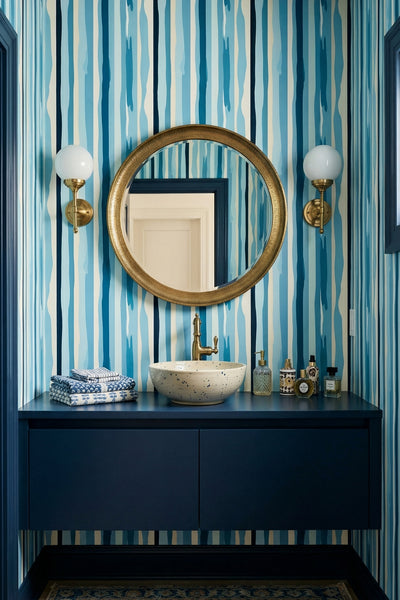 Layered blue vertical stripes on clean ivory wallpaper in a powder room.