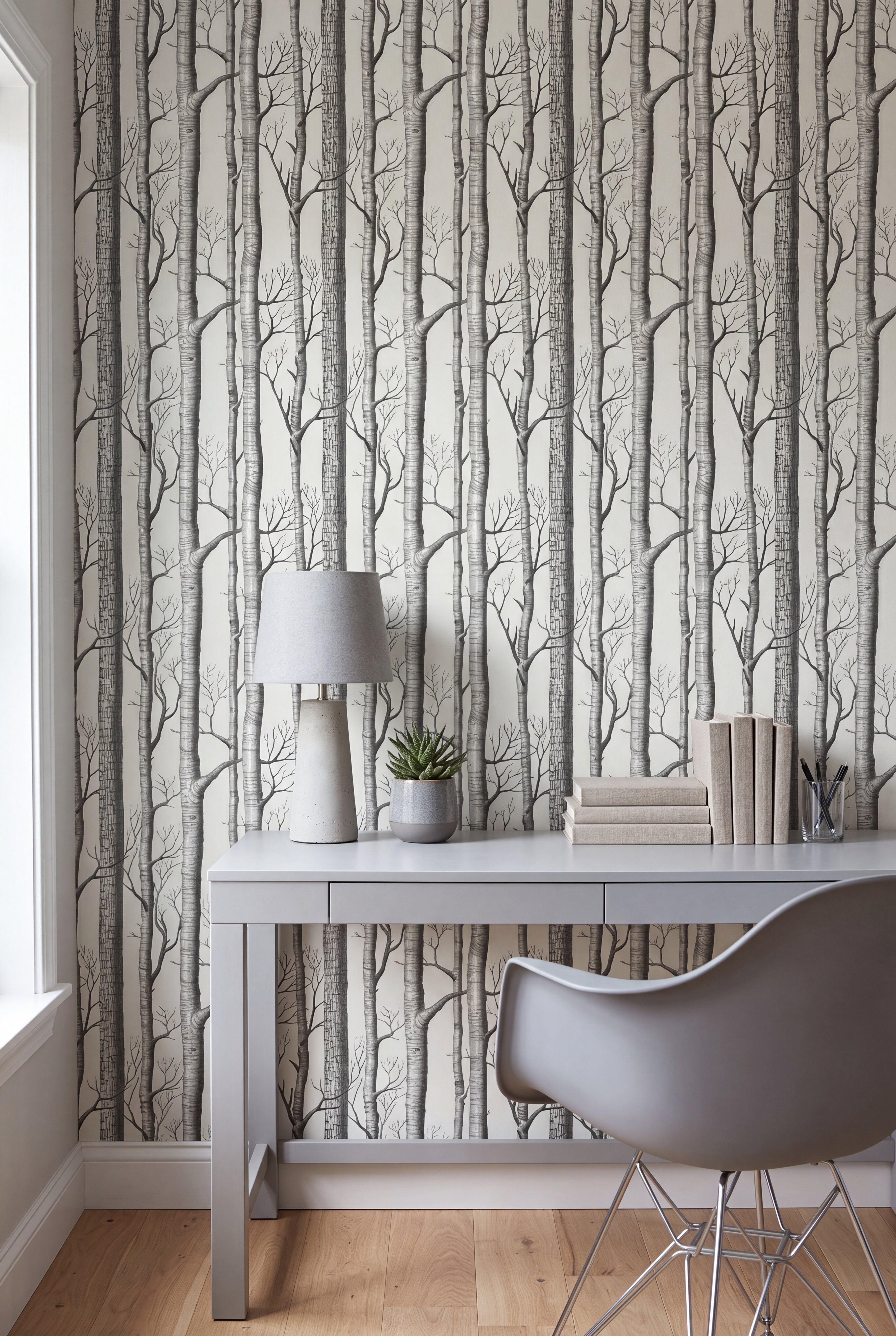 Slender gray birch trunks on pale cream wallpaper in a home office.
