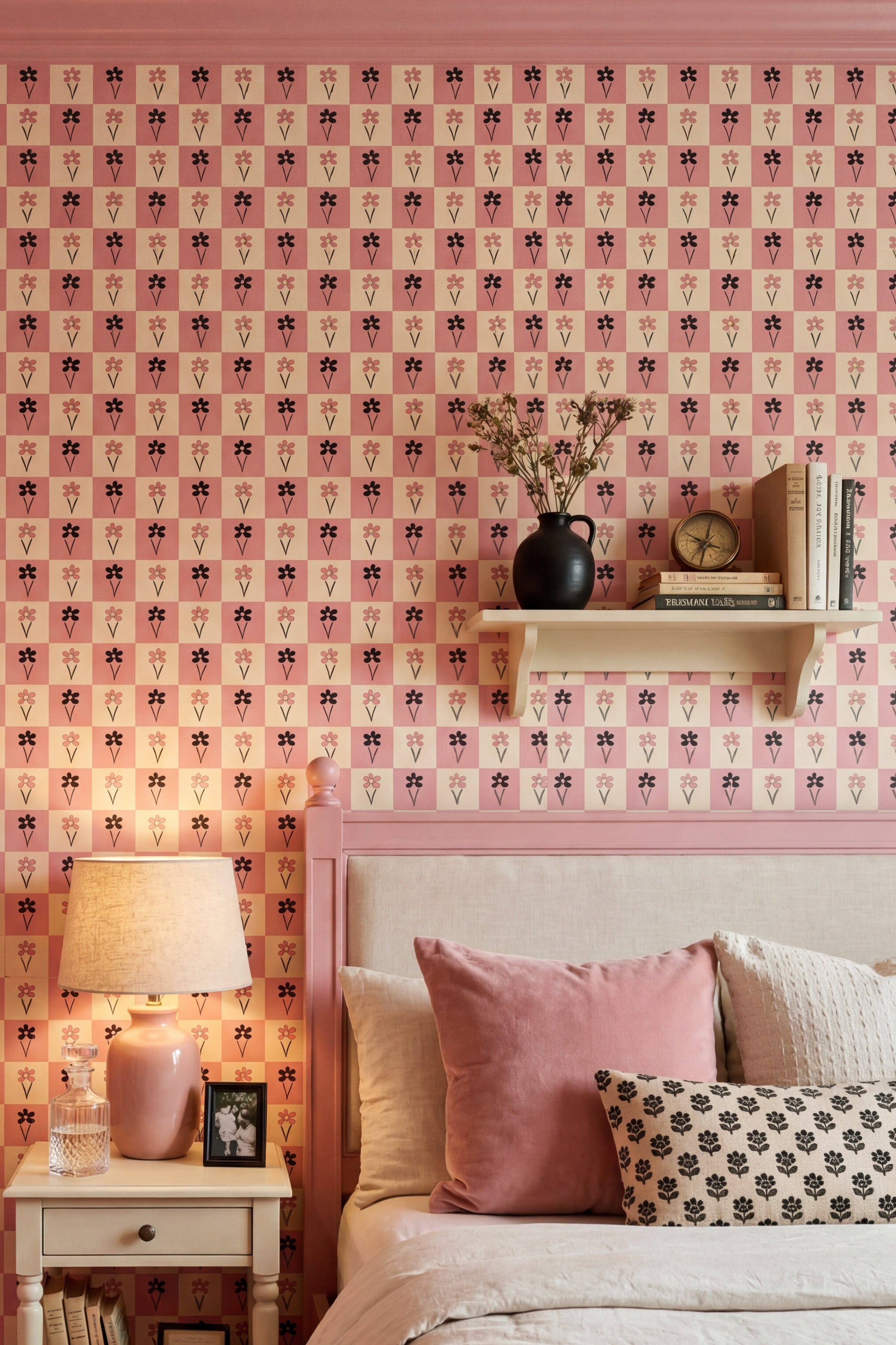 Blush and black daisies on a pink checkerboard wallpaper in a bedroom.