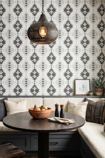 Bold black Southwest geometric motifs on white wallpaper in a cozy nook.