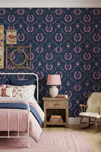 Pink horseshoes and florals on deep navy cowgirl wallpaper in a bedroom.