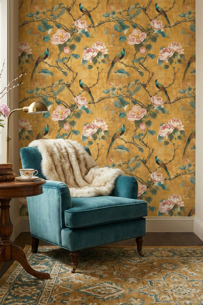 Pink and teal songbirds among lotus blooms on ochre wallpaper in a reading corner.