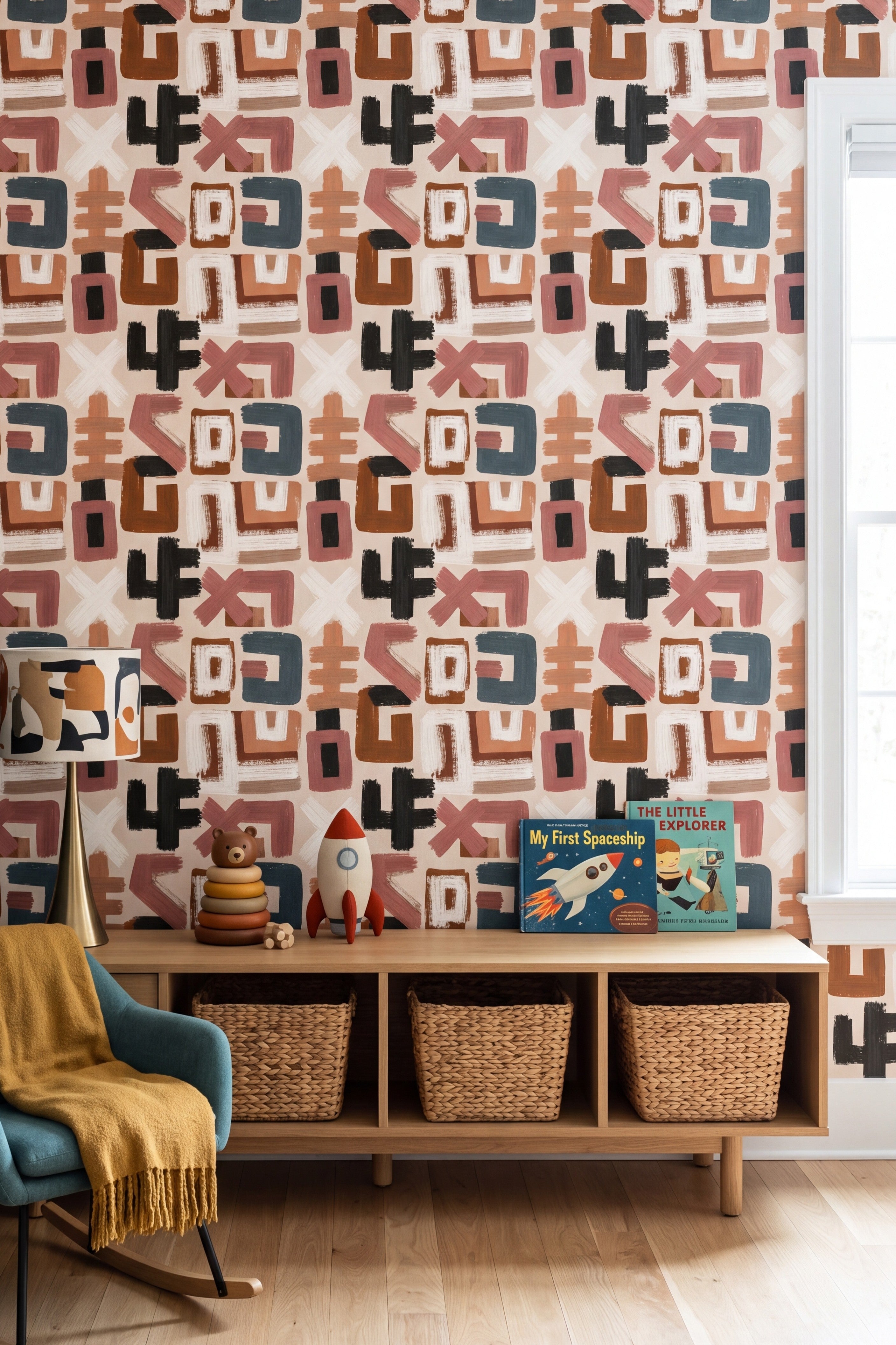 Loose brush stroke shapes in pink teal and rust on cream wallpaper in a child's room.