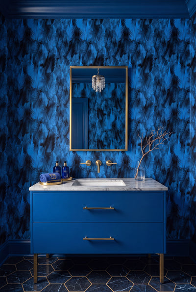 Soft overlapping deep blue feathers on moody wallpaper in a powder room.