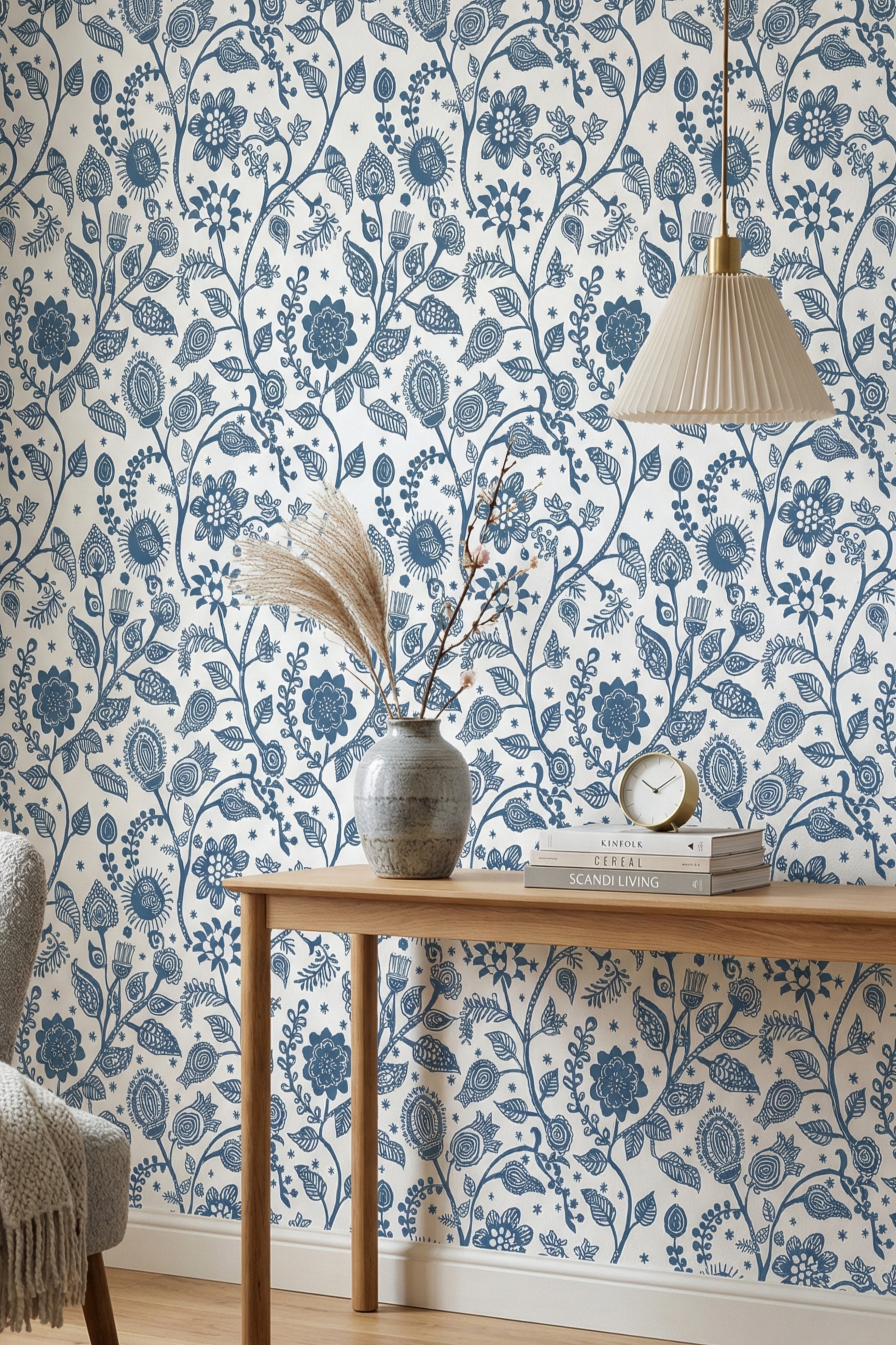 Blue folk-art blooms and vines on a light Scandinavian wallpaper in a reading corner.