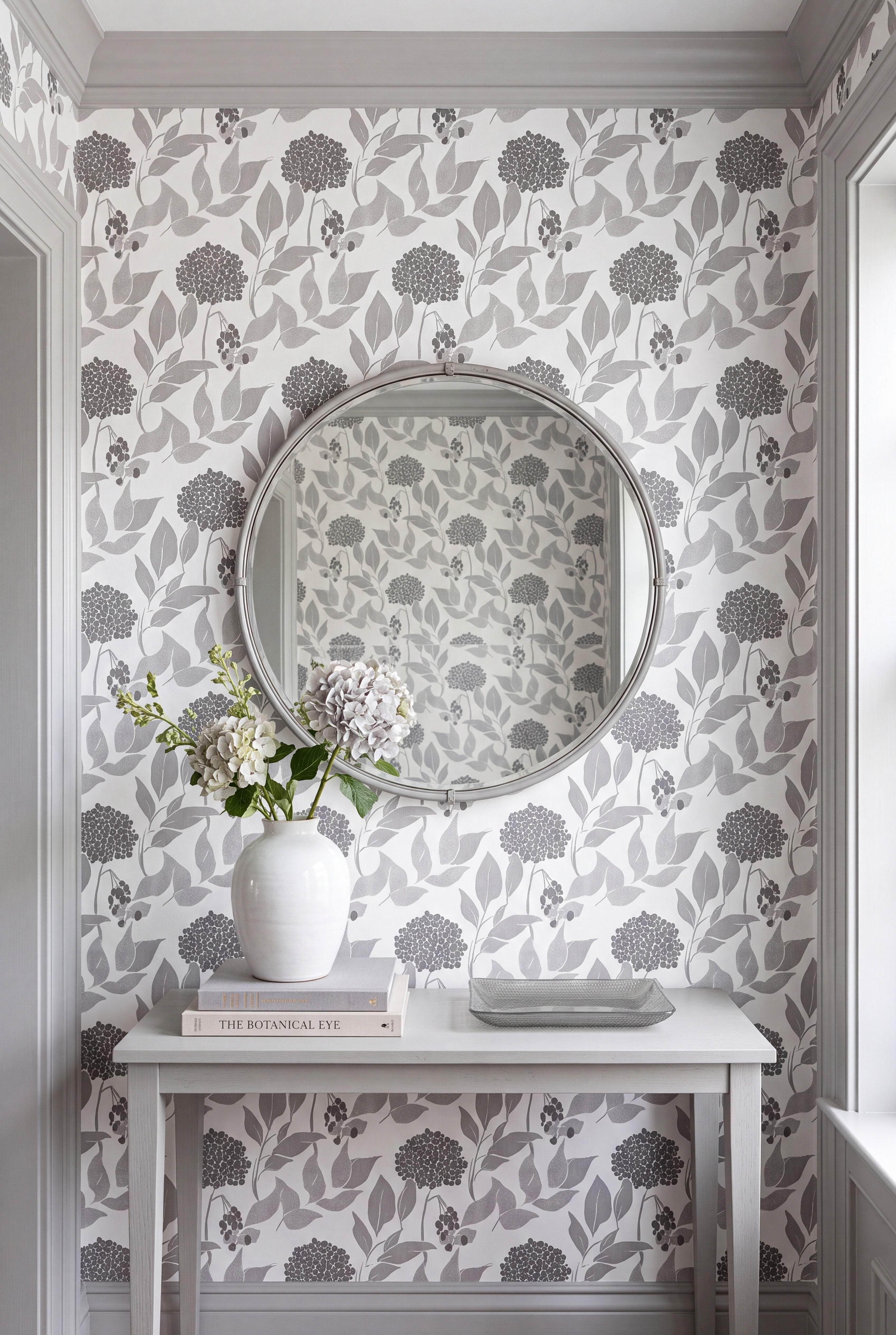 Gray and charcoal layered leaf wallpaper on soft white in an entryway.