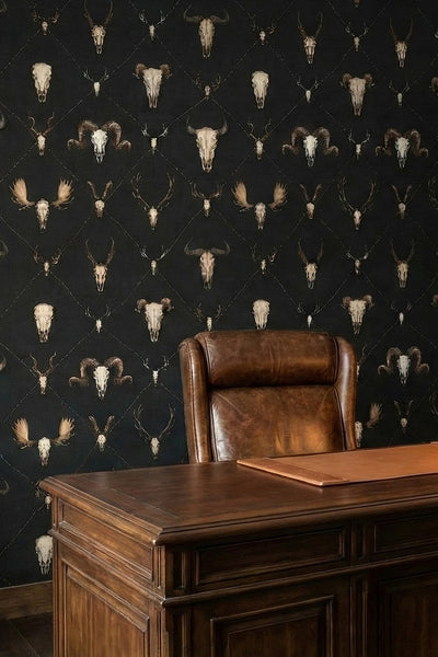 Longhorn skulls and barbed wire on a deep black wallpaper in a home office.