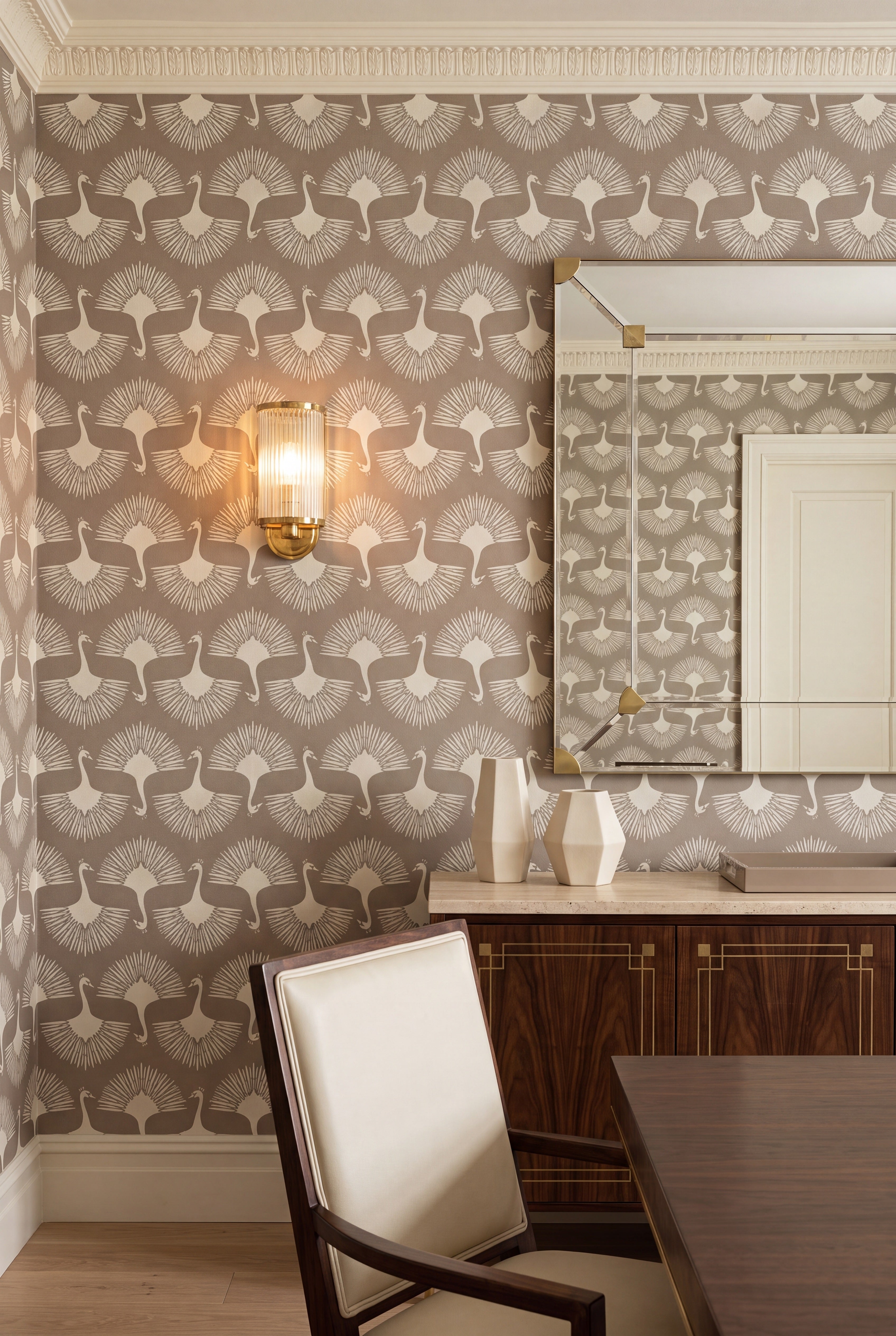 Stylized taupe peacocks in a Deco wallpaper covering a dining room wall.