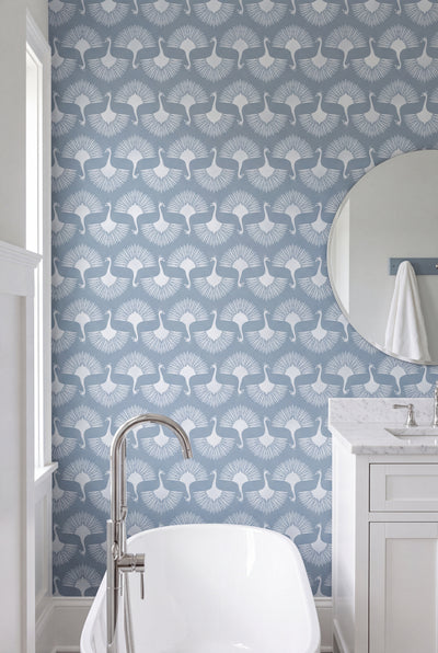 Powder blue peacocks on a pale Deco wallpaper in a bathroom.