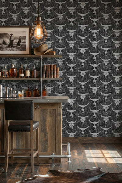 Black and grey longhorn skulls in sunglasses on a Western wallpaper in a home bar.