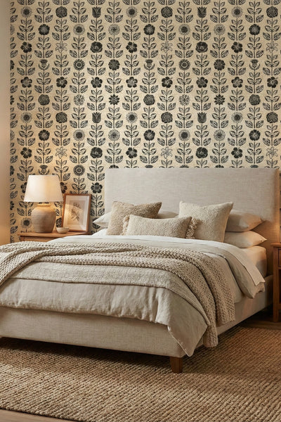 Black block-print flowers on a warm neutral folk wallpaper in a bedroom.