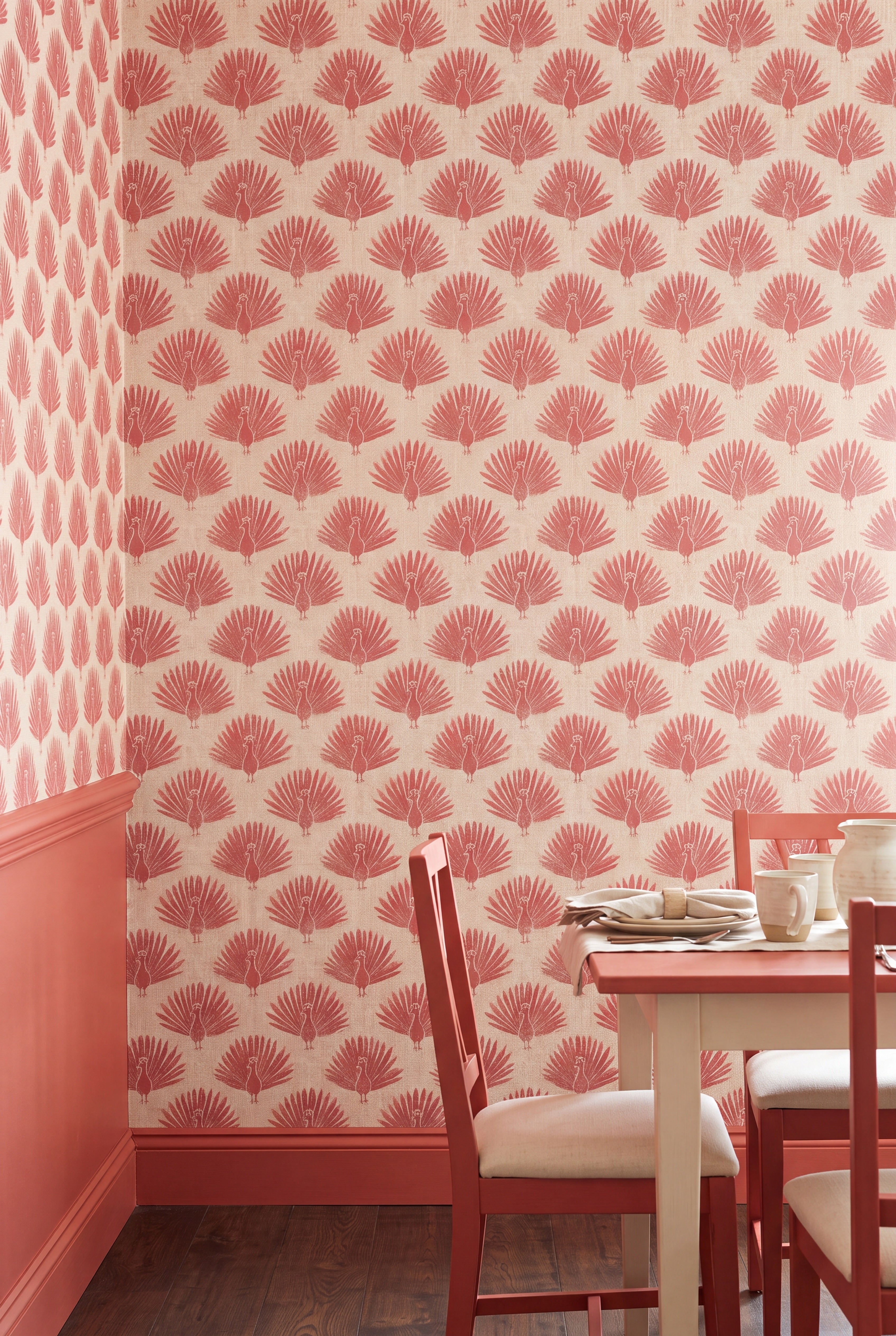 Dusty rose peacock fans on warm beige wallpaper in a dining room.