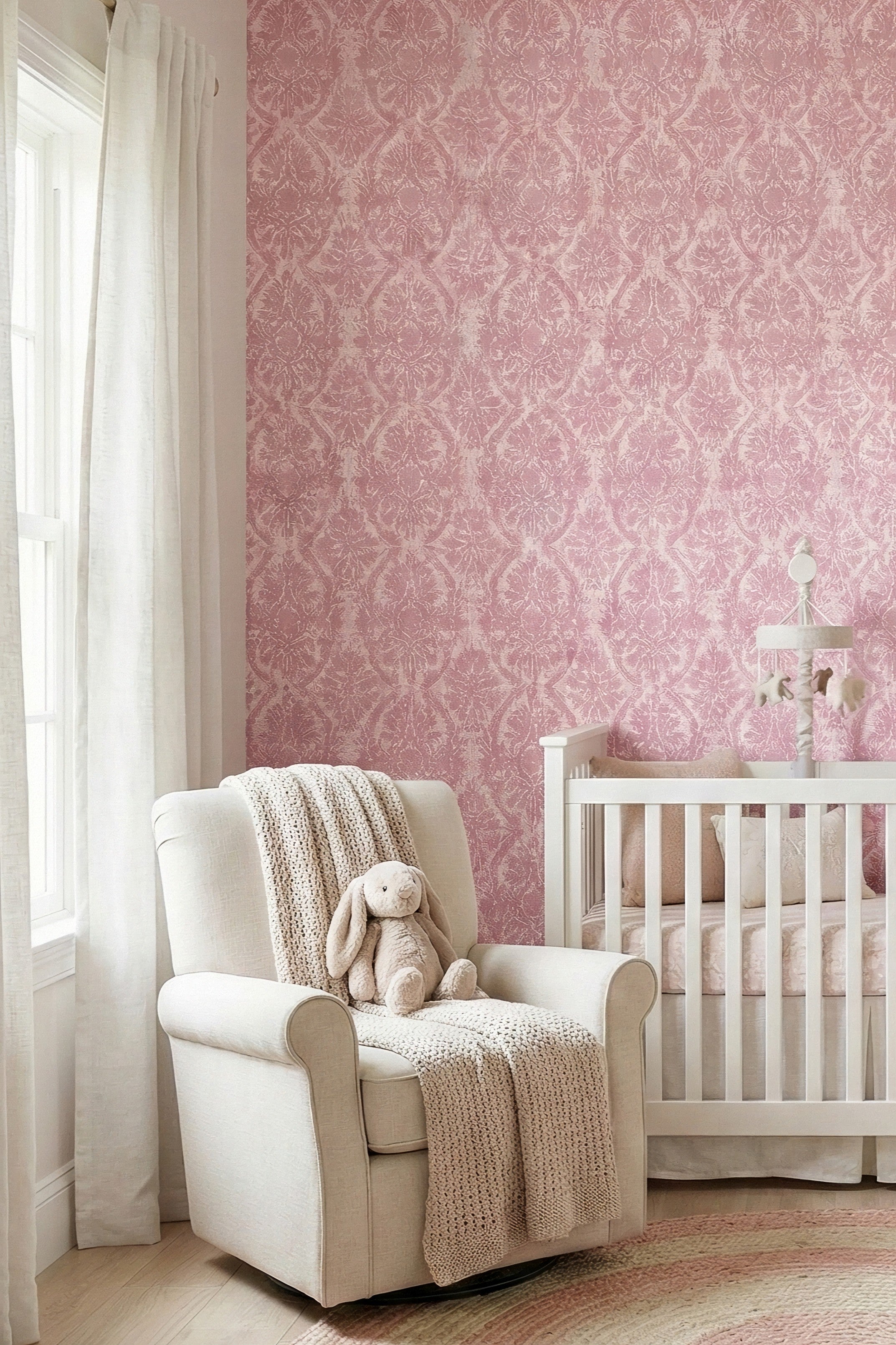 Soft pink damask scrollwork on a light wallpaper in a nursery.
