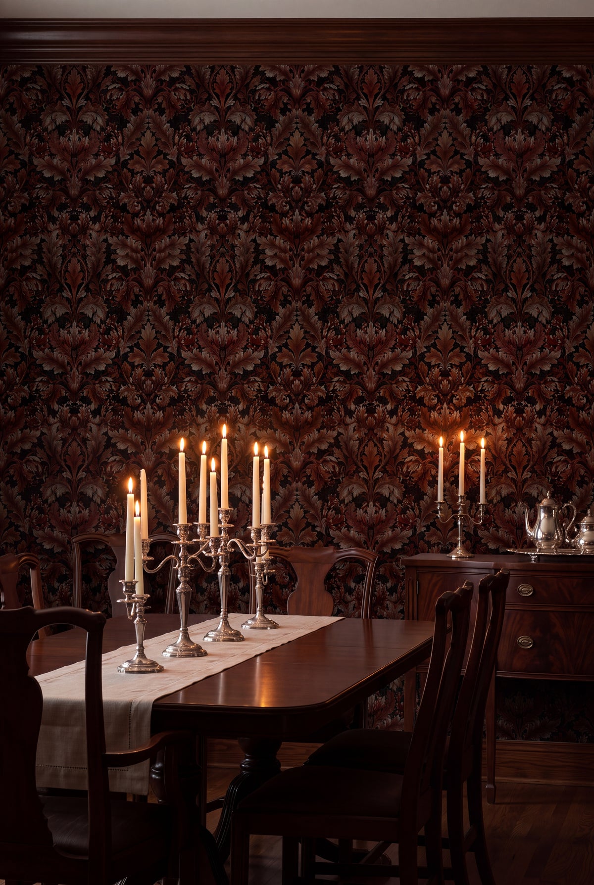 Oxblood red acanthus plumes on a black Victorian damask wallpaper in a dining room.